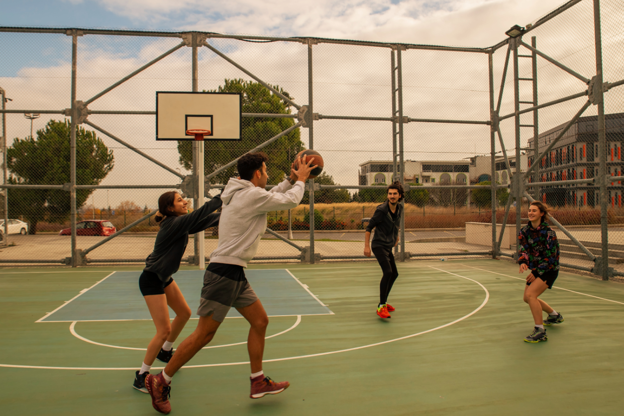High school aged students playing basketball on an outdoor court