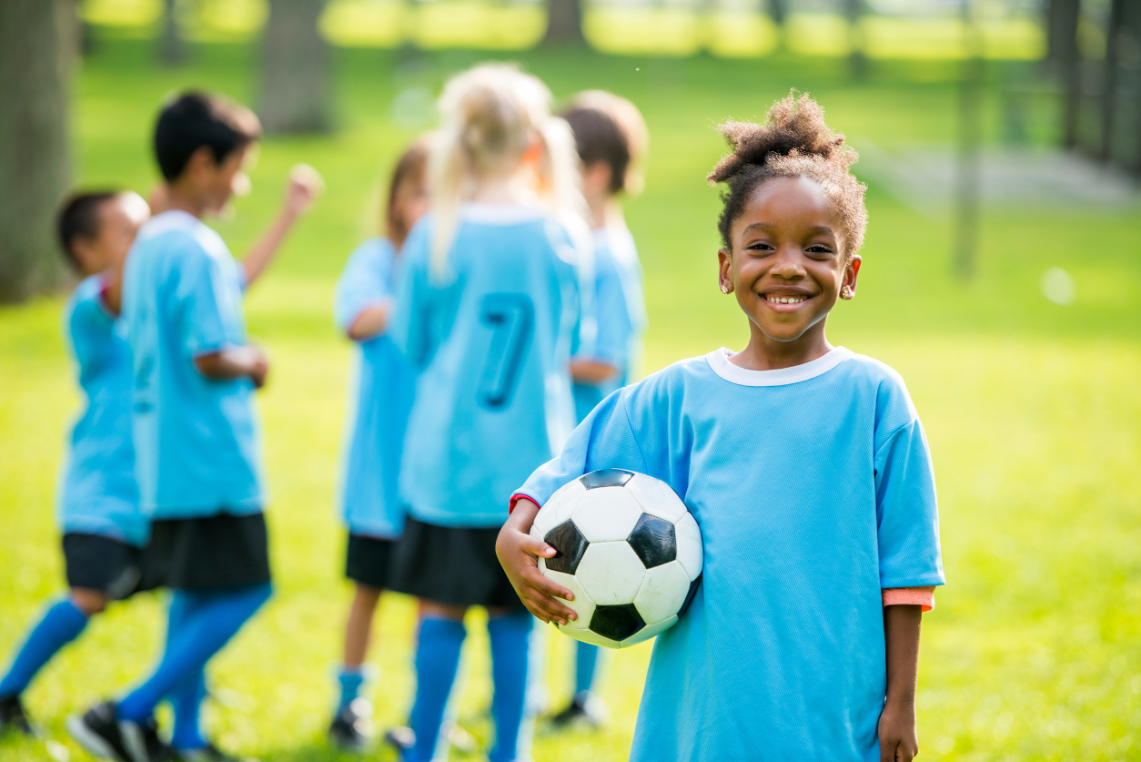 Young child holding a soccer ball and smiling