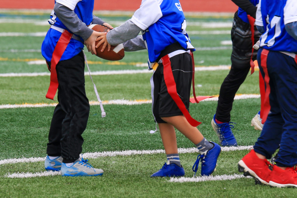 Kids playing flag football passing the ball to eachother